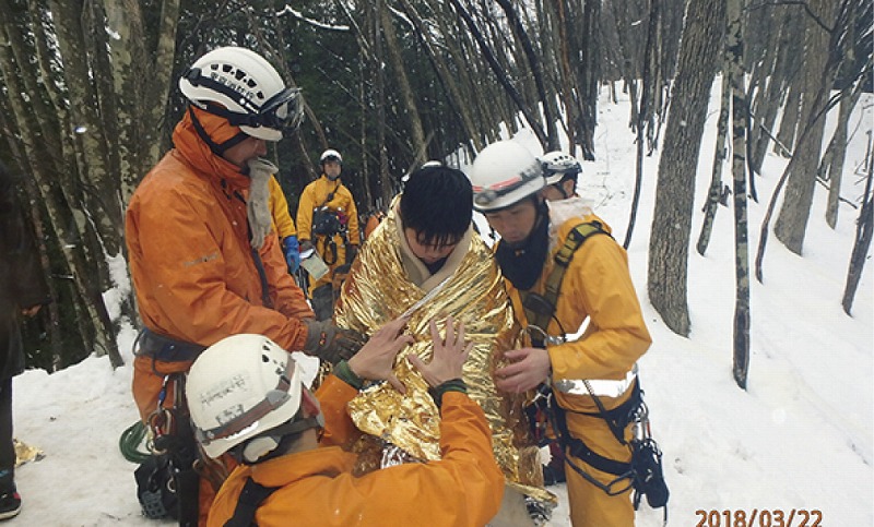 要救助者を背負い下山させる前に、サバイバルシートで保温する。