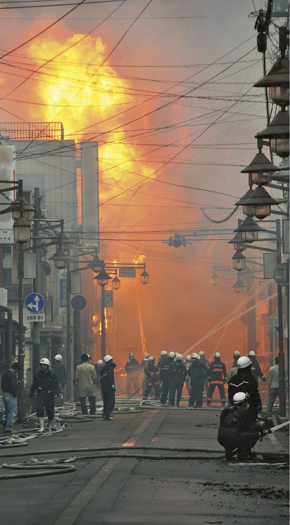 激しい炎と煙で道もよく見えない状況の出火元付近の商店街。糸魚川市消防本部の隊と消防団が懸命の消火活動に当たっている。写真：糸魚川市提供