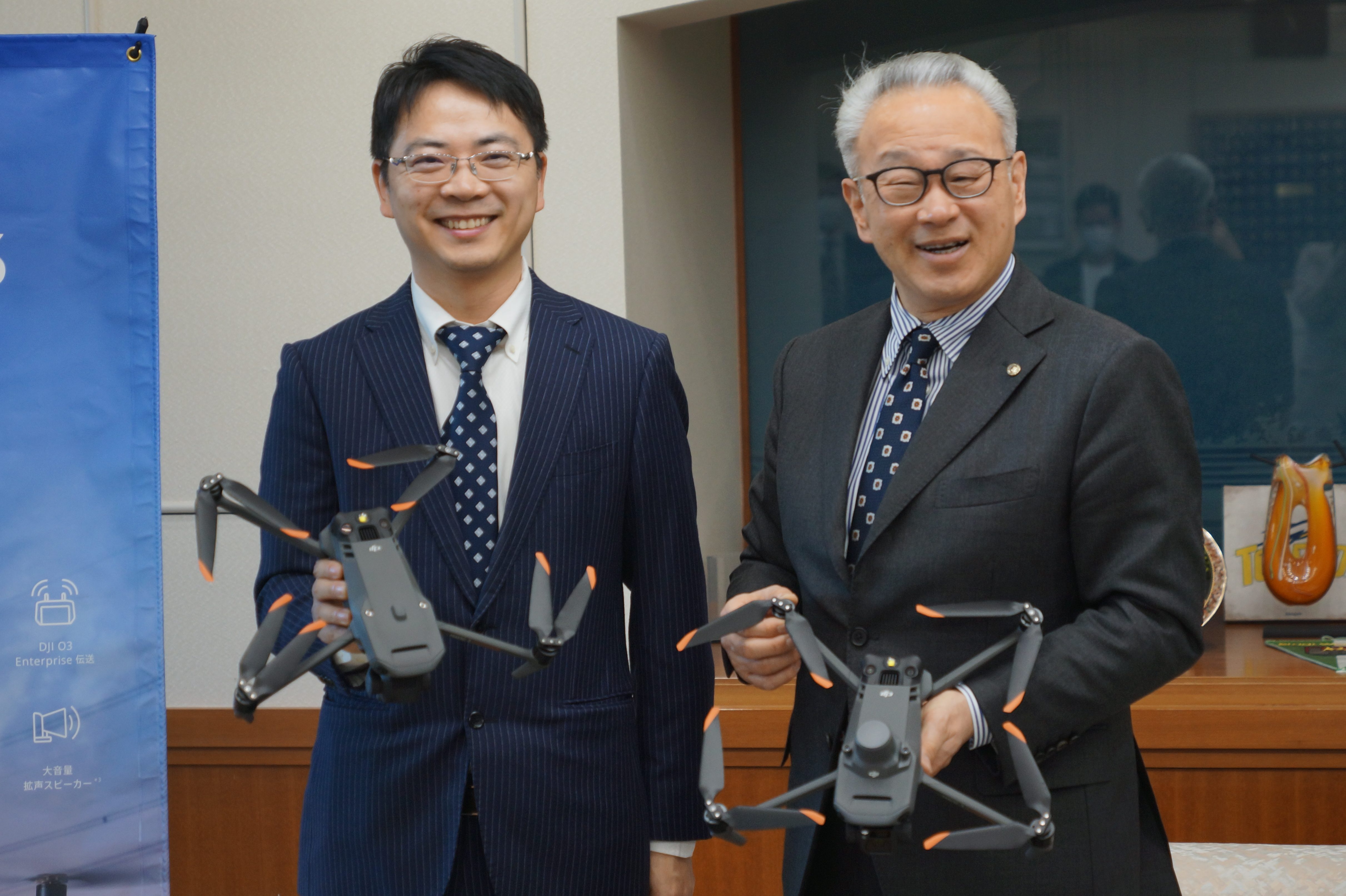 対談後にDJI社の最新ドローンを手にして記念撮影に応じる浅井市長（右）と呉代表（左）